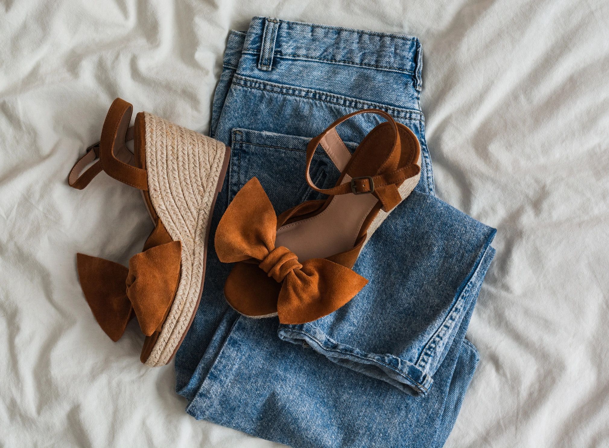 Women’s clothing and accessories flat lay on a light background